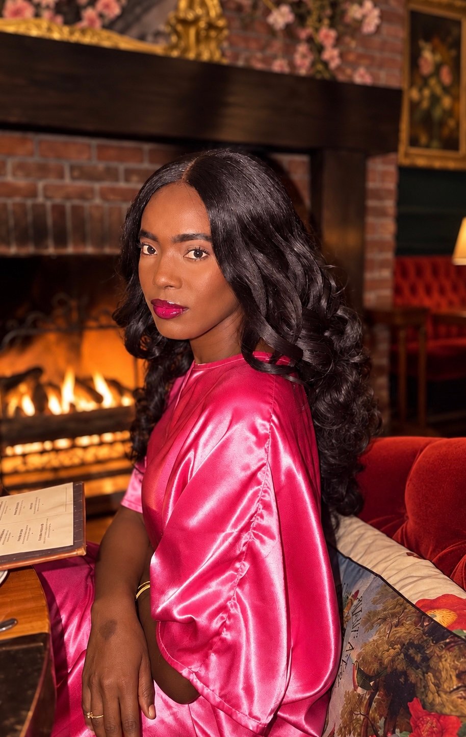 Portrait of romance author Eyta Jade seated by a fireplace